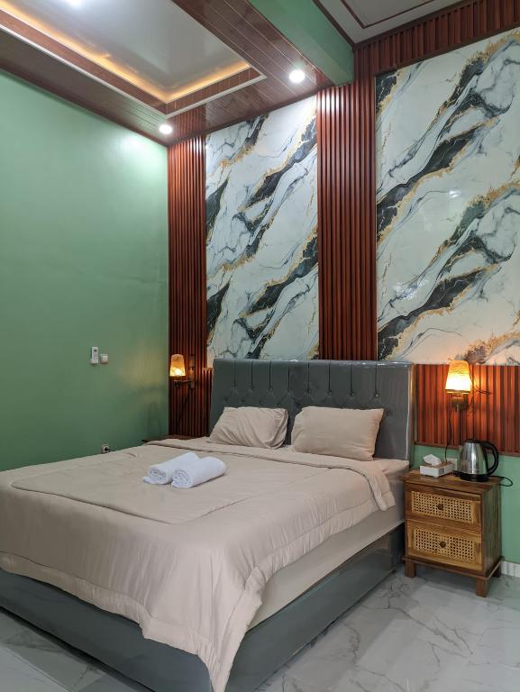 a bedroom with a large bed with a painting on the wall at Nanda Harum Villa in Sangyang