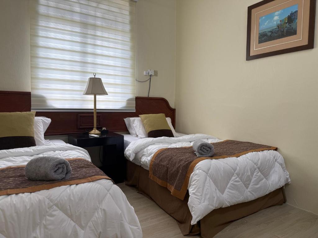 a bedroom with two beds and a window at Lanisa Staycation Mesra in Kampong Padang Bungor