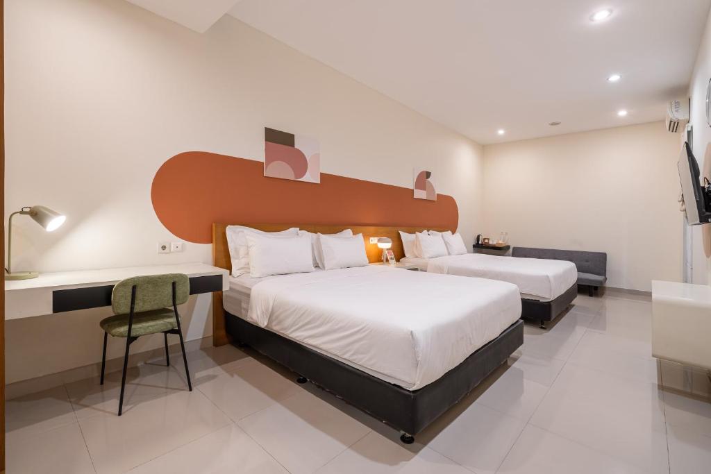 a hotel room with two beds and a desk and a bathroom at Cove Amayana in Surabaya