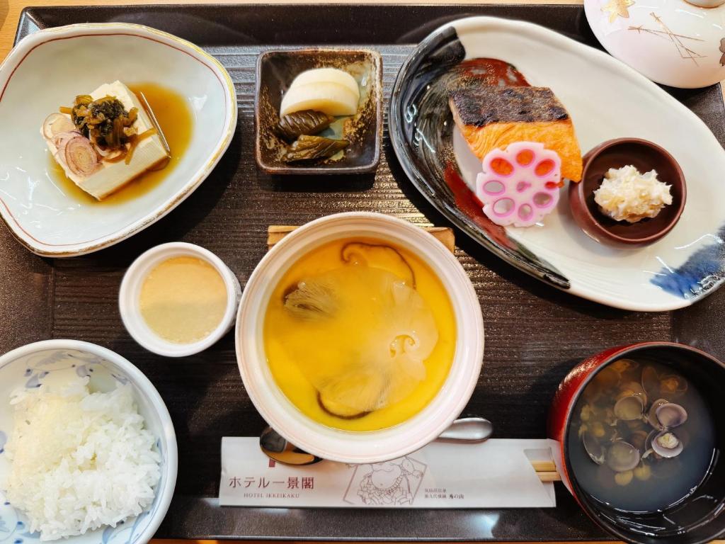a table with plates of food and a cup of soup at Hotel Ikkeikaku in Kesennuma