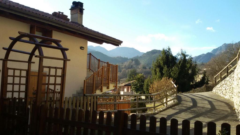 a fence next to a house with mountains in the background at Ledro Charlotte House in Molina di Ledro