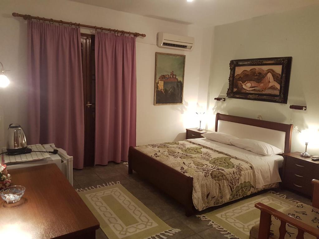 a bedroom with a bed and a table with two lamps at Sofia Rooms in Kalabaka