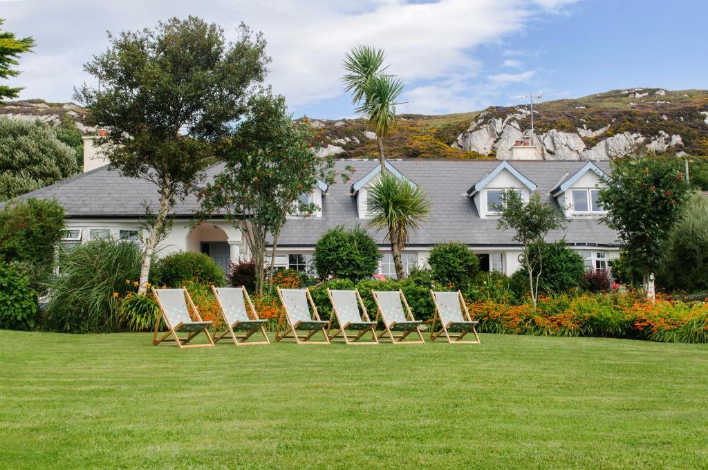 uma fila de cadeiras num relvado em frente a uma casa em Hillside Lodge B&B em Clifden