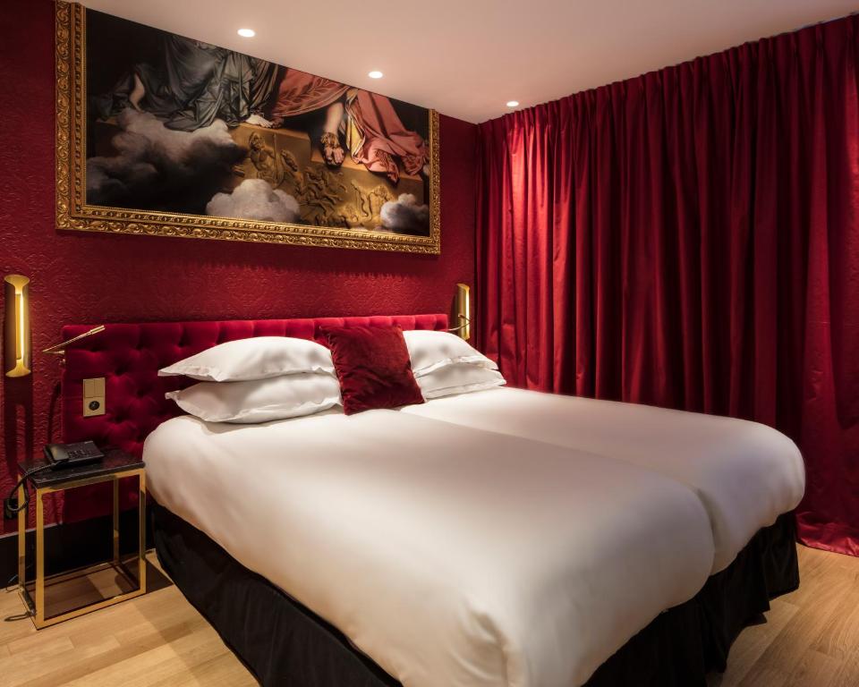 a hotel room with a large bed and a painting on the wall at Eiffel Petit Louvre in Paris