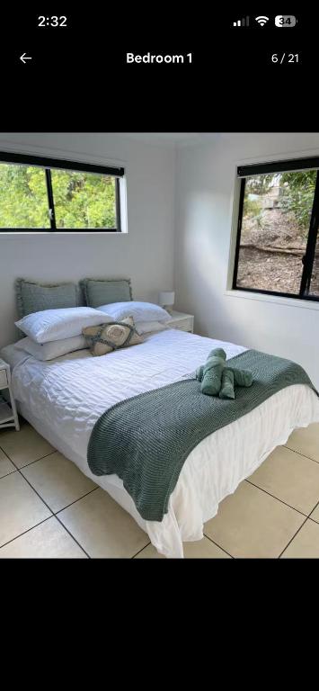 a bedroom with a large bed with two windows at Hinterland Ocean Vista Escape in Maroochy River