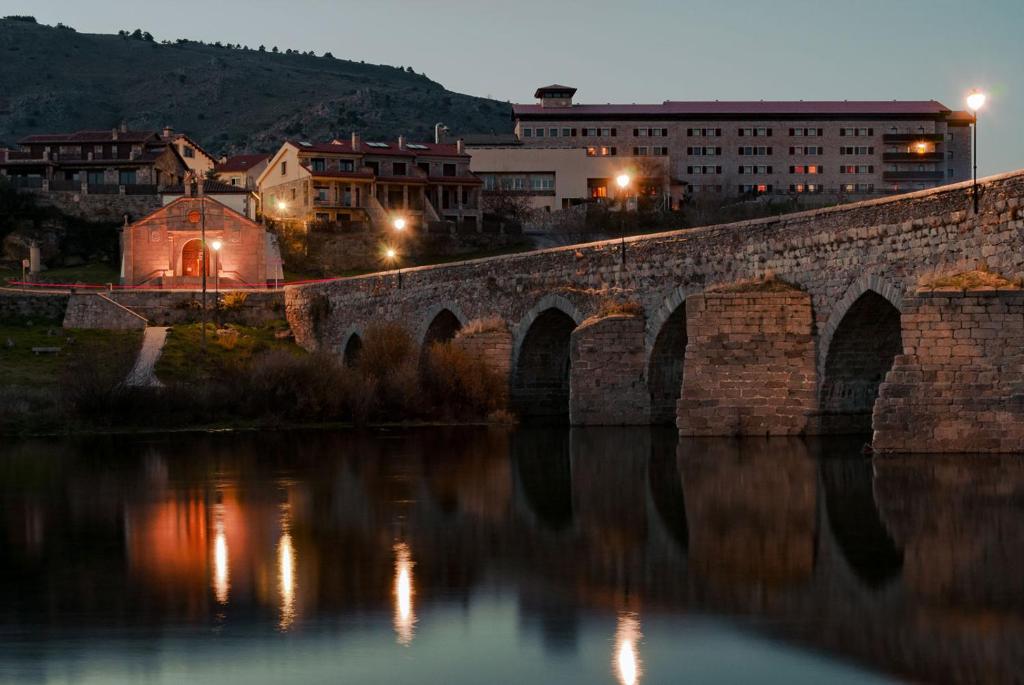 Hospedium Hotel Mirador de Gredos في إل باركو دي أفيلا: جسر حجري قديم فوق نهر في الليل