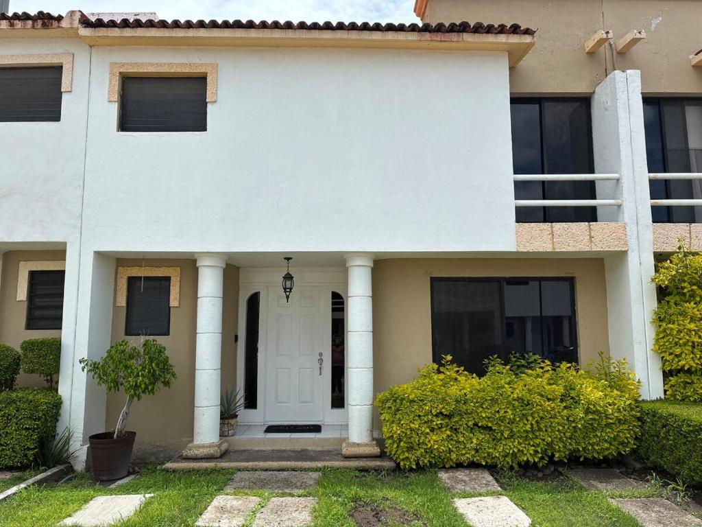 a white house with a white door and columns at House check-in anytime after 3 pm in Jurica