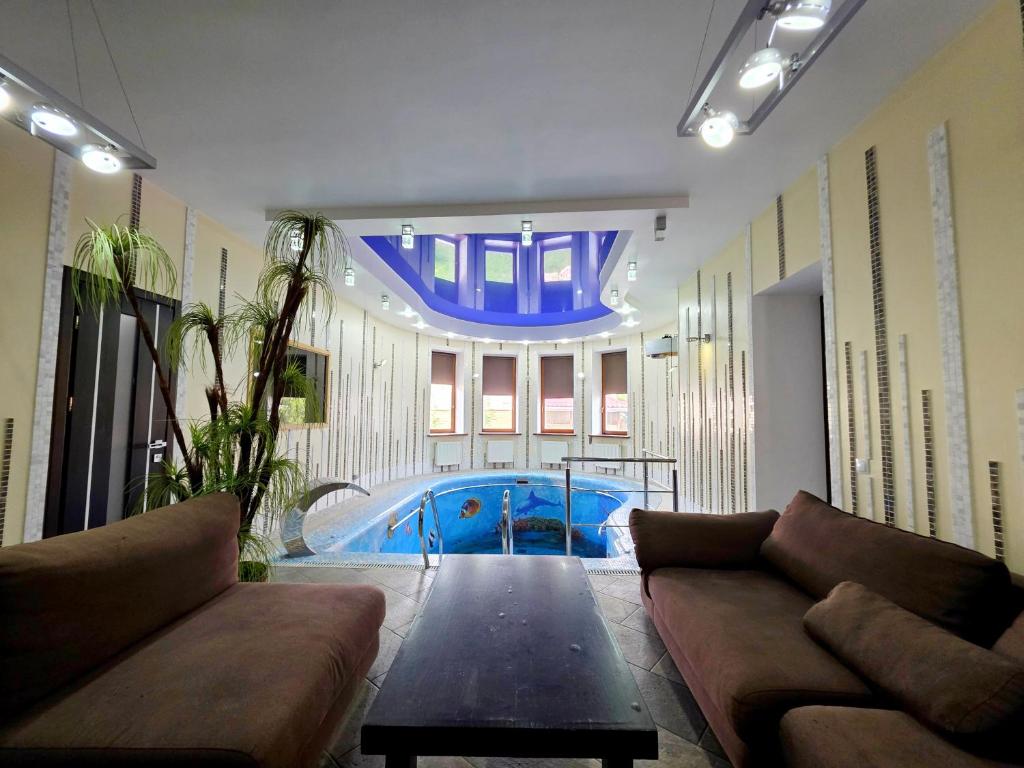 a living room with a couch and a swimming pool at Вілла з 6 Спальнями Басейн Більярд Сауна BBQ Укриття in Odesa