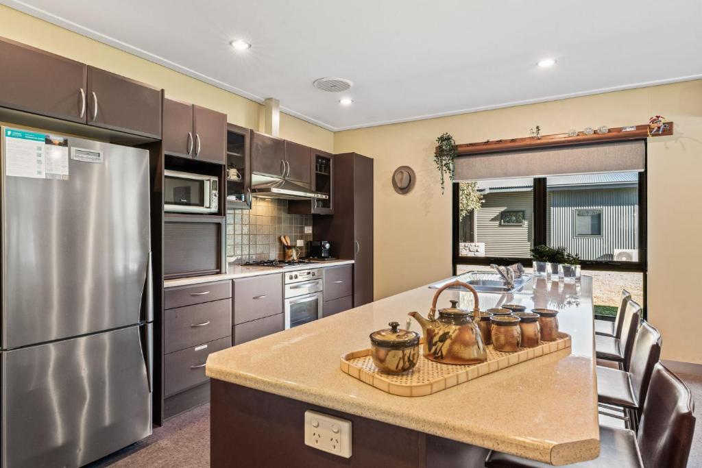 a kitchen with a stainless steel refrigerator and a table at Kickenback Lodge - 3BR Lodge l Gym l Indoor Pool l Tennis l WiFi l Air-Con in Crackenback