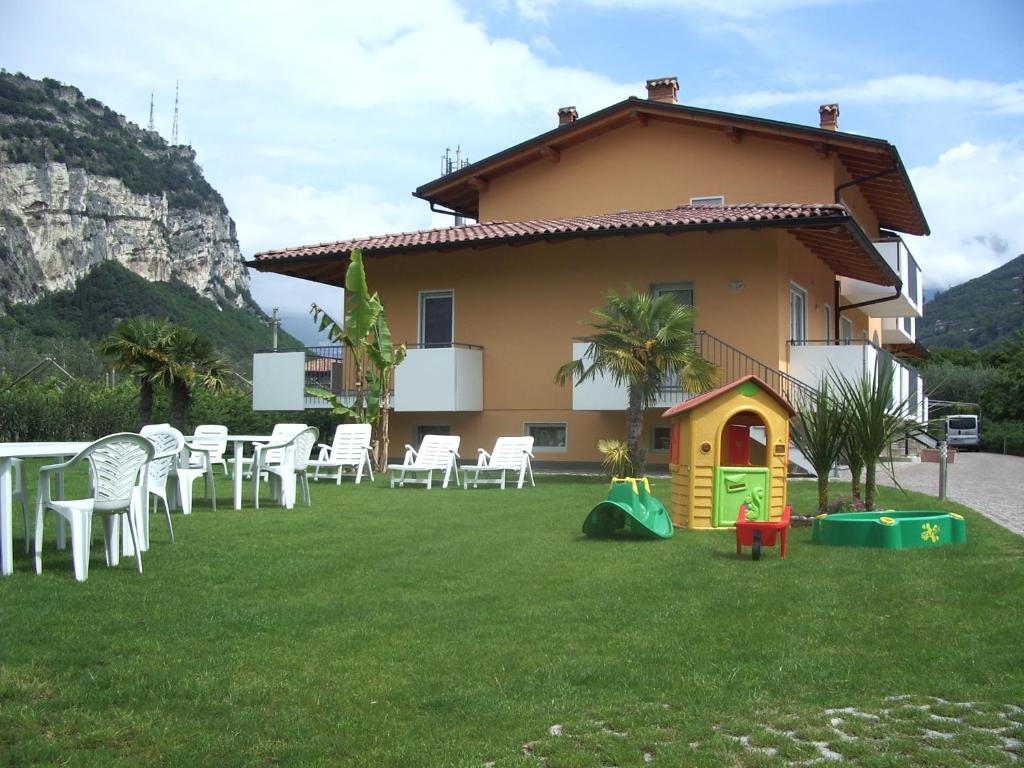 una casa con césped con sillas blancas y una casa para perros en Agritur Laura, en Nago-Torbole