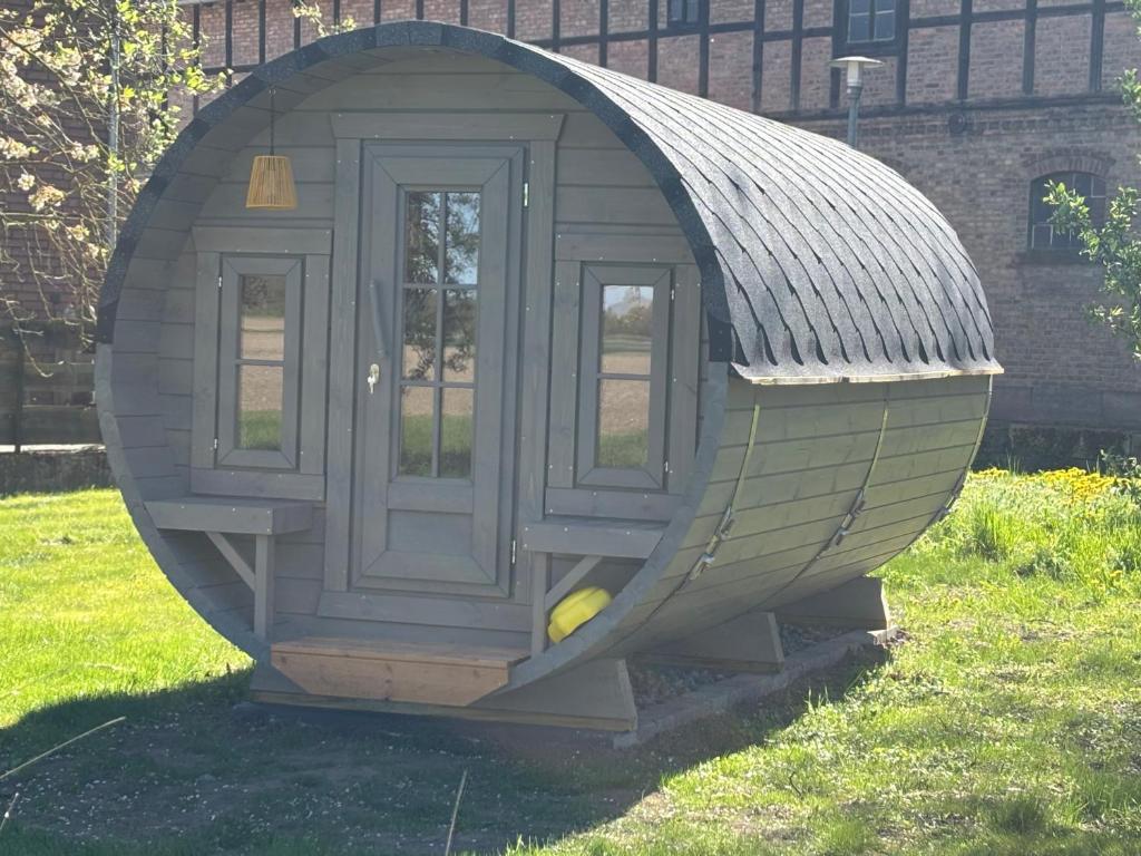 a small house with a door in the grass at Obstgarten im Warnetal- Campingfass Wabe in Gielde