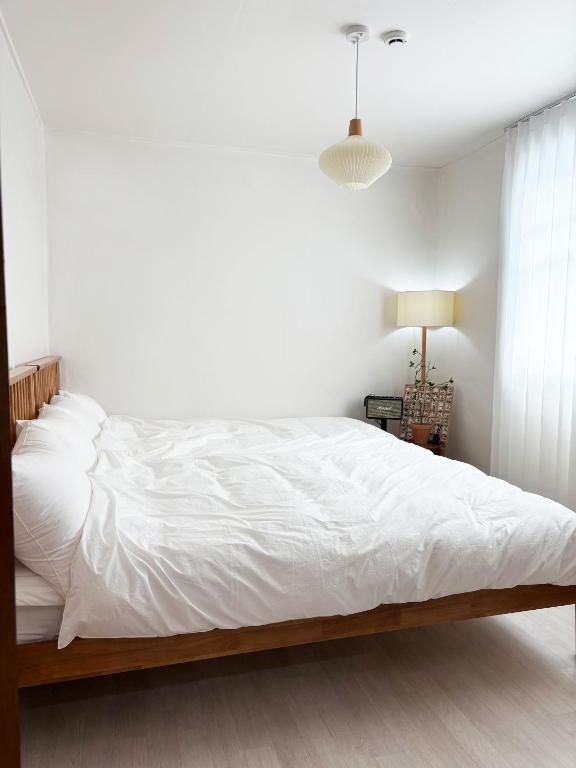 a white bedroom with a large bed with white sheets at 지하철 2분, 침대3, 4인 최적, 5인 가능, 홍대 경복궁 명동 동대문 이동편리 in Samgong