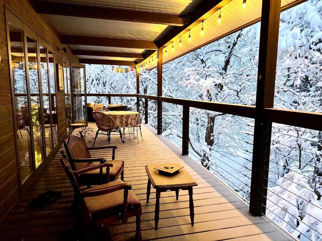 a screened porch with a table and chairs and snow covered trees at Bears Den Mountain Lodge in Hakuba