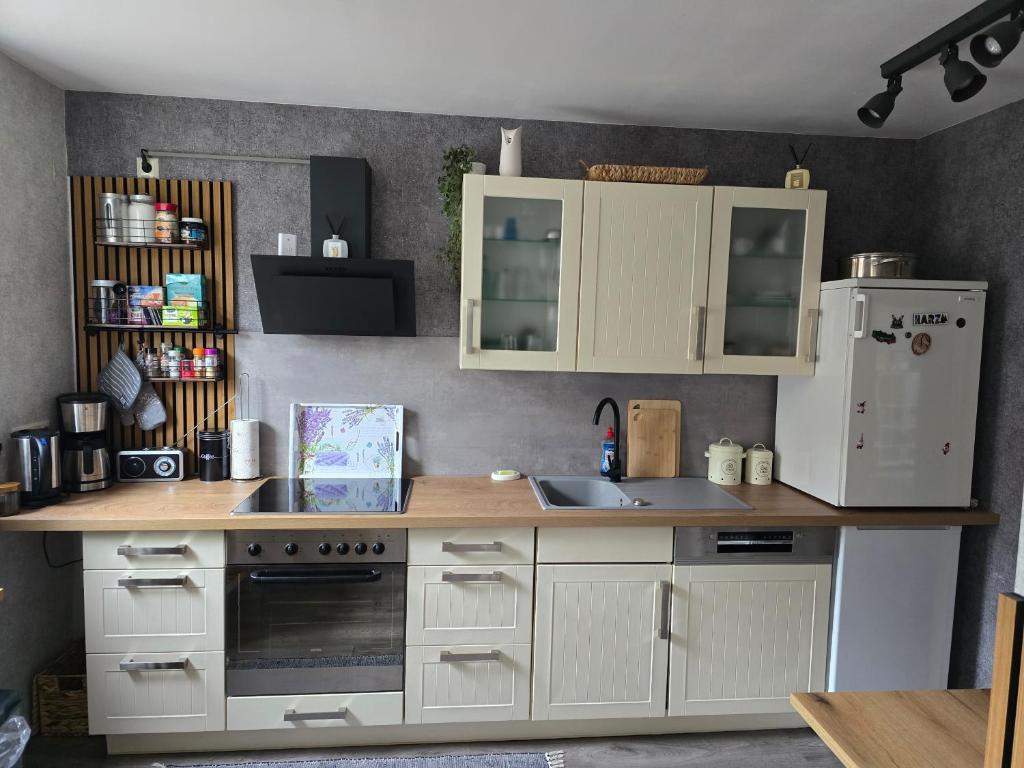 a kitchen with white cabinets and a sink and a refrigerator at Tenneberger 1 in Ilsenburg