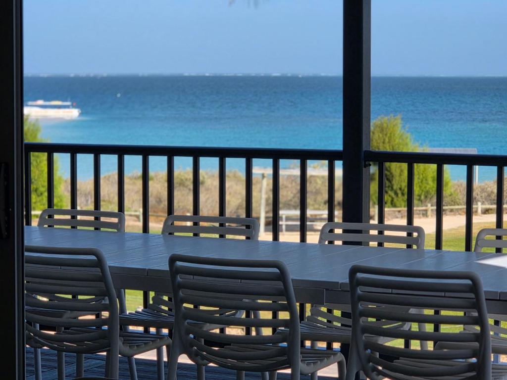 a table and chairs on a balcony with the ocean at Ningaloo Coral Bay – Bayview in Coral Bay