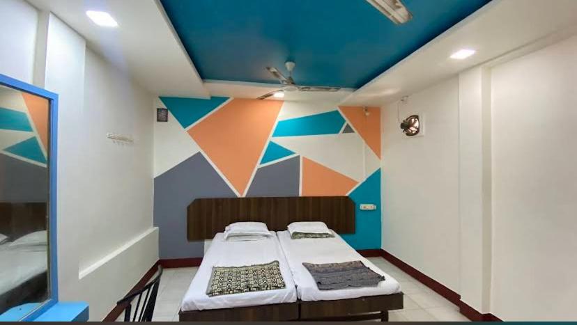 a bedroom with two beds and a colorful wall at Muktai Lodge in Solapur