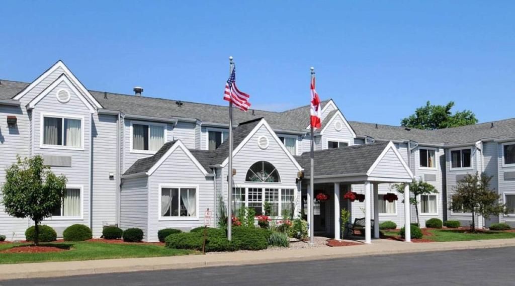 a white house with an american flag in front of it at CenterWay Hotel Buffalo North Near University in Tonawanda