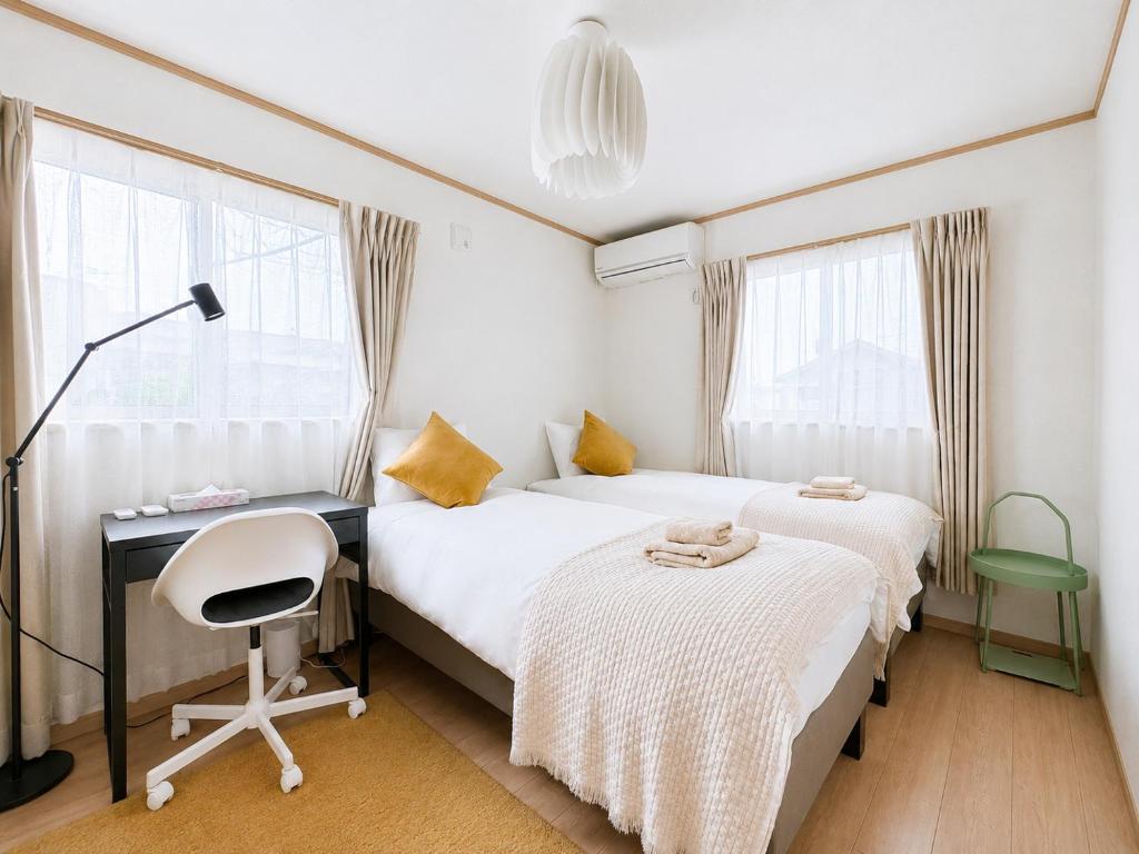 a bedroom with two beds and a desk and a chair at KANAU in Tokyo