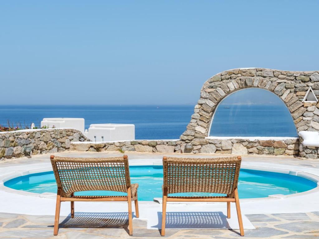 two chairs sitting next to a swimming pool at Aqua Lumen Private Pool Villa, Mykonos in Agios Ioannis Mykonos