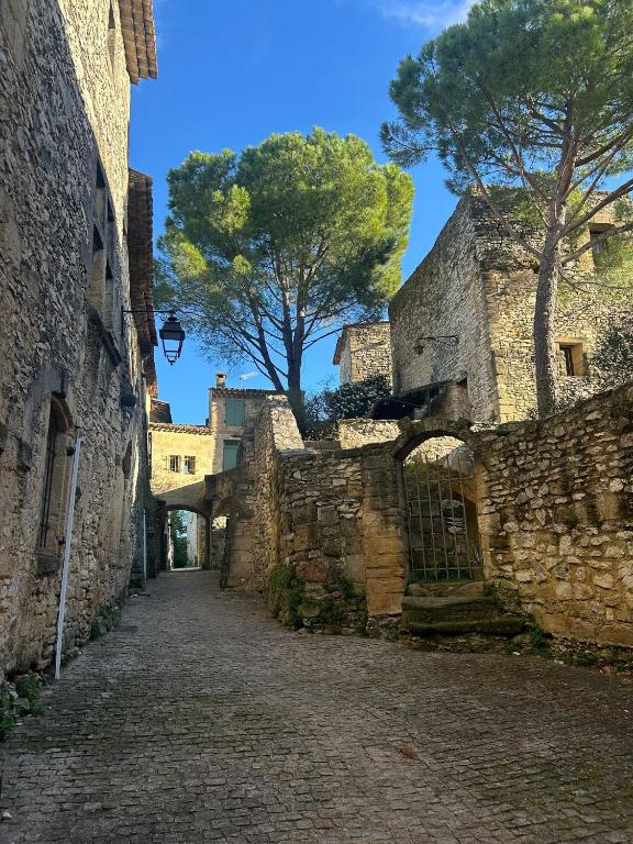 an alley in an old stone building with a tree in the background at Maison Florence in Valliguières