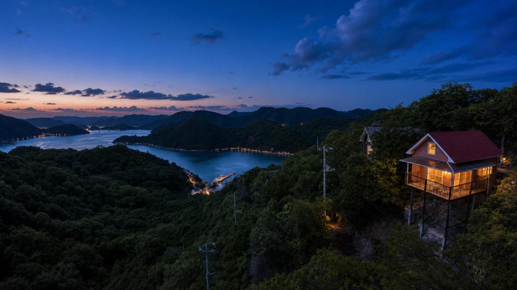 a house on the side of a mountain at night at Simple Island Villa Surrounded by Nature Peaceful Stay in Bizen