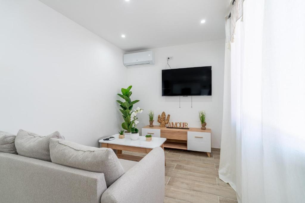 a white living room with a couch and a tv at Port-la-Nouvelle 4p in Port-la-Nouvelle