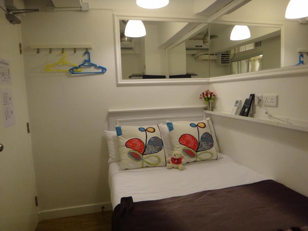 a room with a bed with two pillows and a mirror at Apple lnn Causeway Bay in Hong Kong