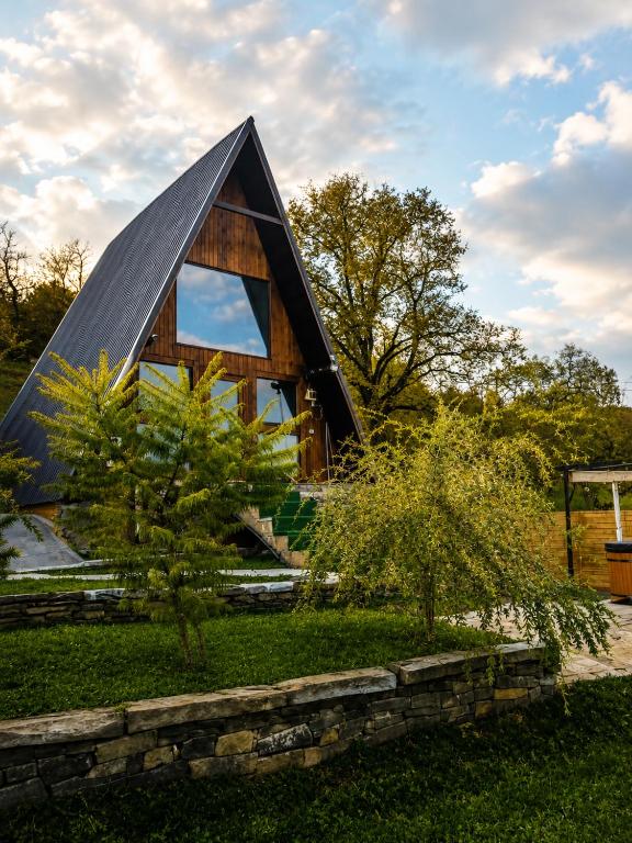 a triangular house with a triangular roof with a tree at Căsuța de pe Vale in Sighetu Marmaţiei