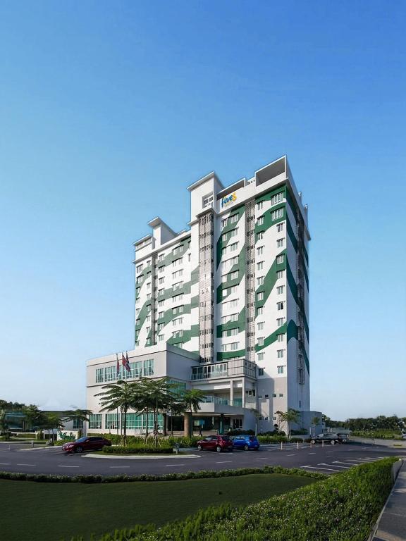 a large white building with cars parked in a parking lot at Fives Hotel Desaru in Desaru