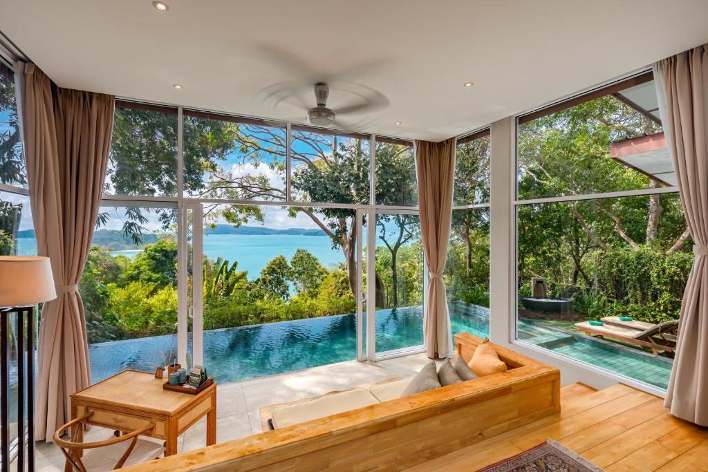 a living room with a large window with a view of the water at Ambong Pool Villas - Private Pool in Pantai Cenang