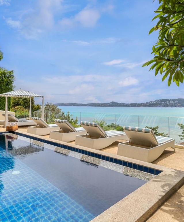 a swimming pool with lounge chairs and the ocean at Oceans Eleven Villa Samui - Oceanfront, Private Pool, Perfect for families and friends in Bangrak Beach