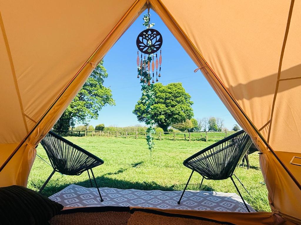 an orange tent with two chairs in a field at Maesbury Meadows in Binegar