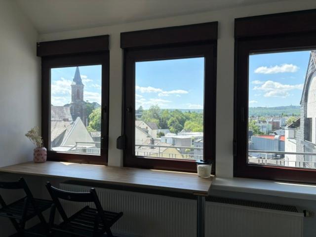 a room with three windows with a table and two chairs at Appartement am Peterstor in Montabaur