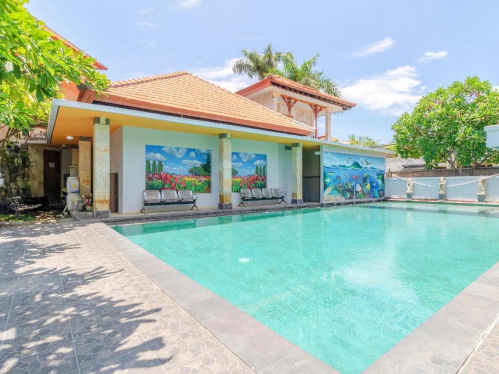 a swimming pool in front of a house at Guntur Hotel Bali in Ketewel