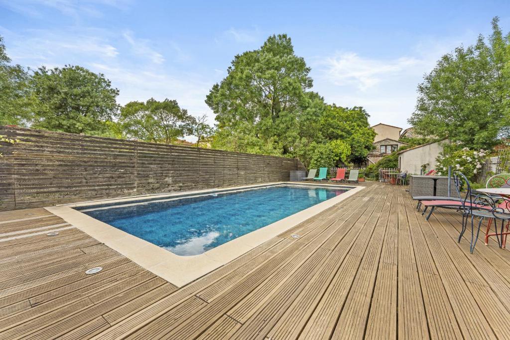 a swimming pool on a wooden deck next to a wall at Mas Abicou in Vézénobres