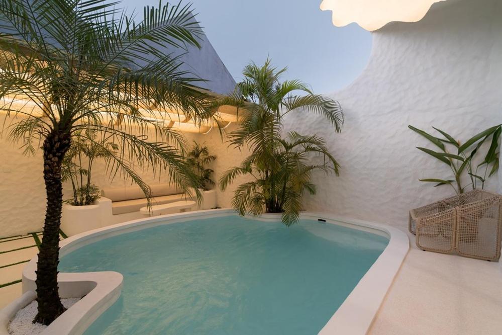 a swimming pool with palm trees in a building at Makyra by Bohemian Jogja Villas in Kejayan