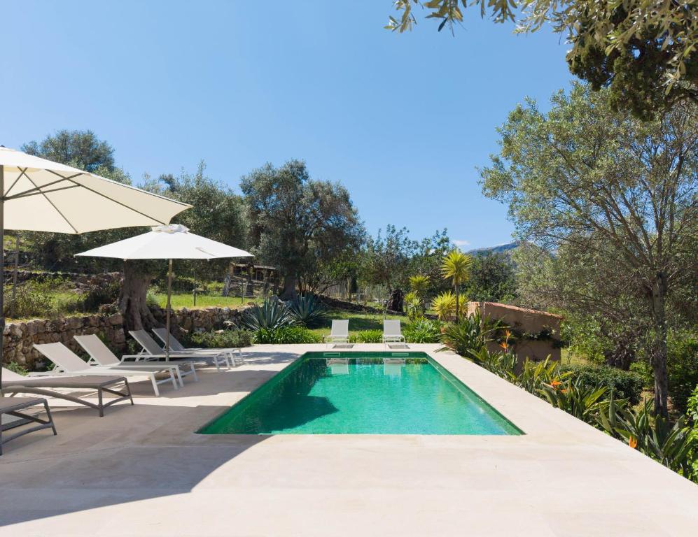 a swimming pool with chairs and an umbrella at Finca Es Coste by Rentallorca in Pollença