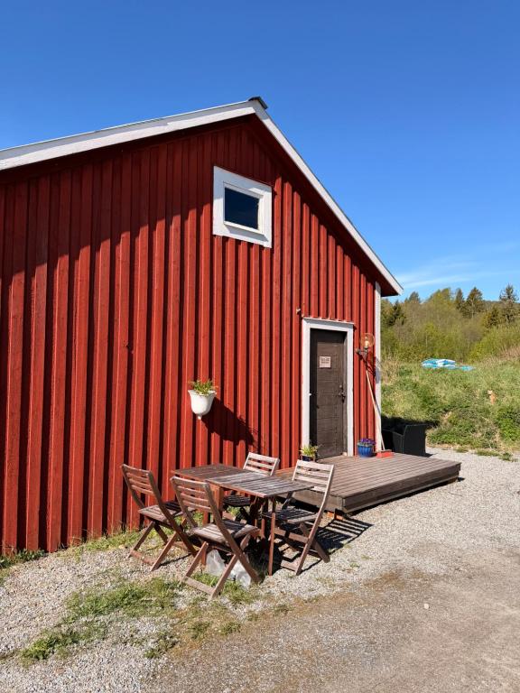 a picnic table and chairs in front of a red building at Folkja gård, gästhus i Höga kusten in Noraström