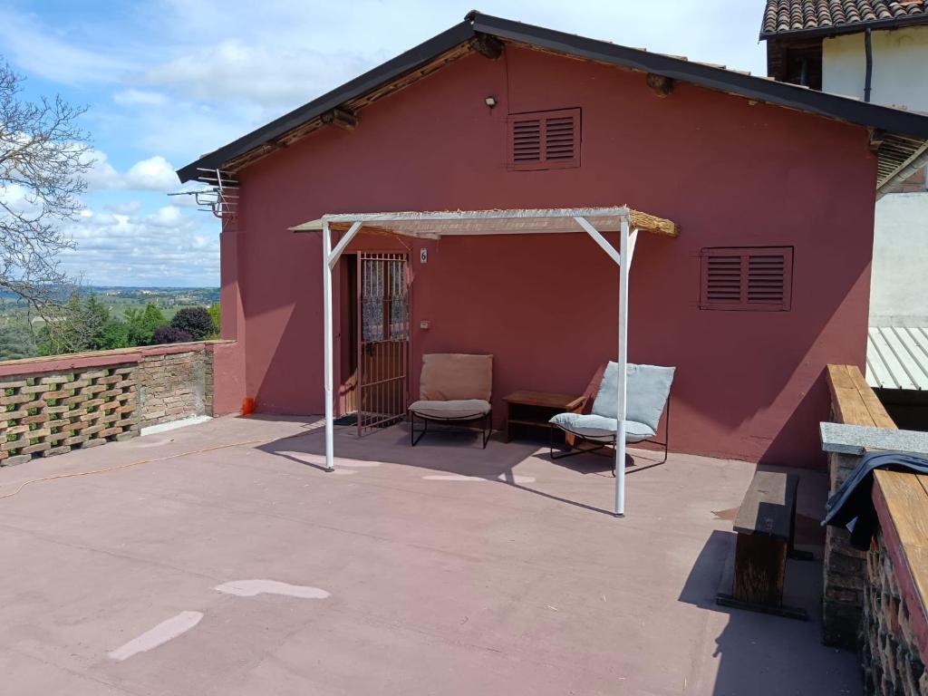a red house with two chairs and a table at Il Rustico di Calosso in Calosso