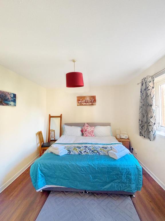 a bedroom with a large bed with a blue blanket at Spacious room close to tram in Edinburgh