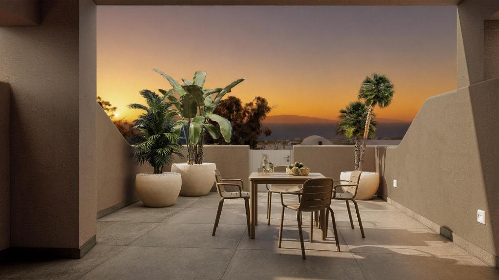 a balcony with a table and chairs and a sunset at Terracotta Sunset Suites in Oia