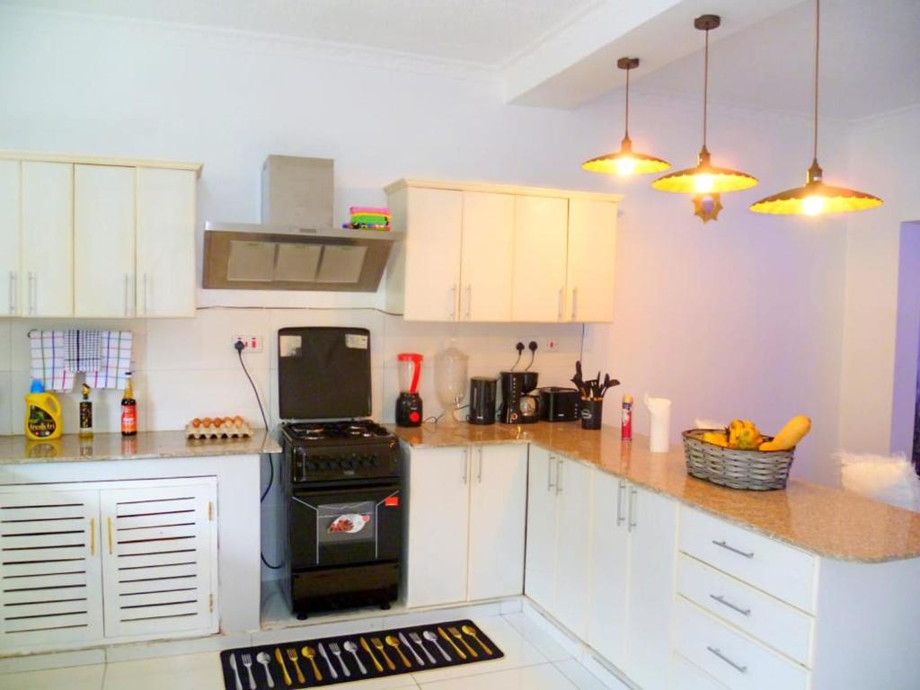 a kitchen with white cabinets and a black stove at Rosa Mystica Diani Bnb in Ukunda Airport