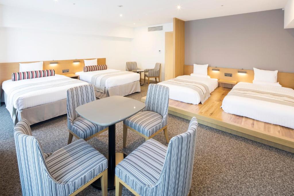 a room with three beds and chairs and a table at HOTEL MYSTAYS PREMIER Omori in Tokyo