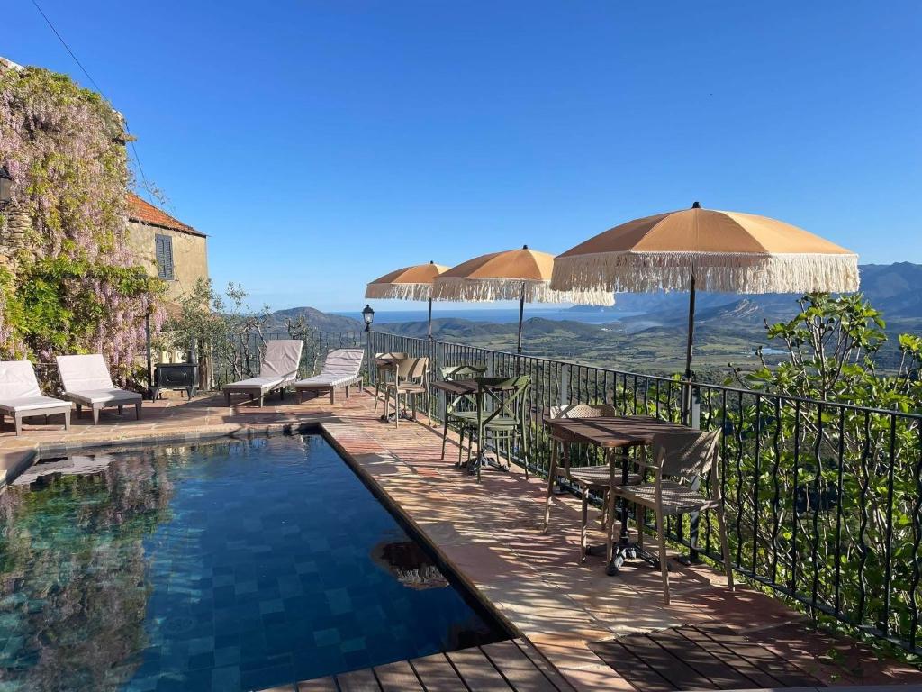 a pool with a table and chairs and umbrellas at Maison D'hôtes Casa Ghjunca in Rapale