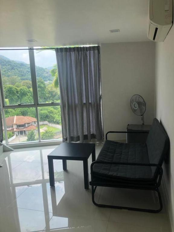 a room with a couch and a table and a window at The Ceo Suites in Bayan Lepas