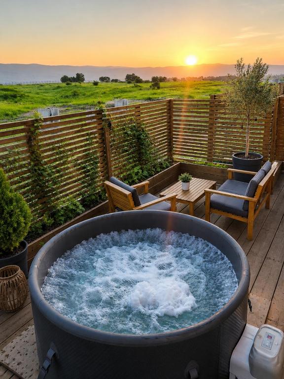 a hot tub with a sunset in the background at בריאה אירוח בטבע in Sha'al