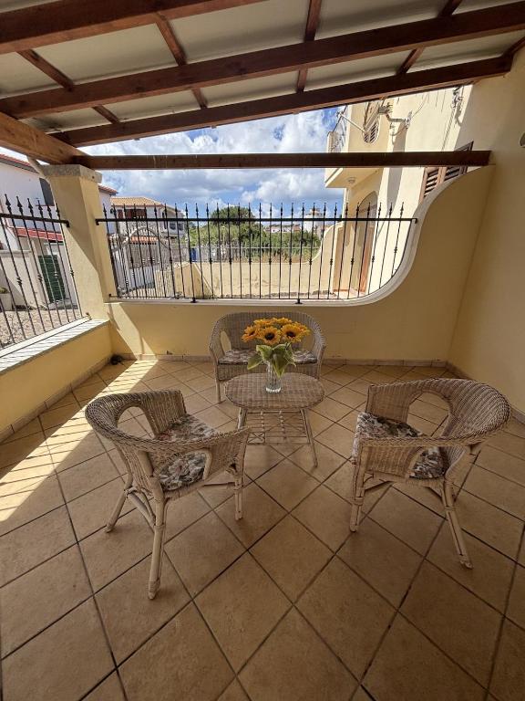 a balcony with a table and chairs and a vase of flowers at Leoni's House in Calasetta