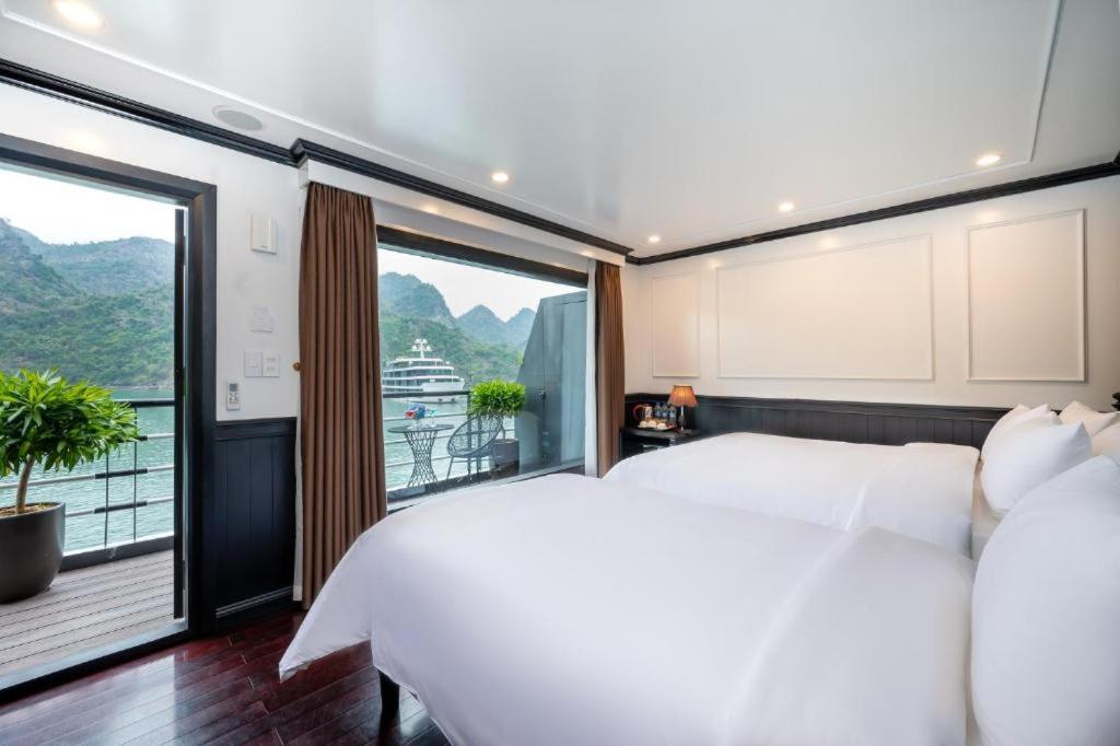 a bedroom with a large white bed and a balcony at Cruise Lan Ha Bay 2 Day 1 Night pick-up from Cat Ba Central in Cat Ba