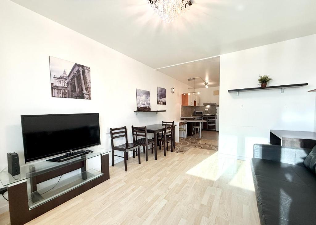 a living room with a flat screen tv and a dining room at Central Warsaw Apartment with Pool & Sauna in Warsaw