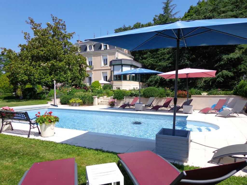 a pool with chairs and umbrellas and a pool at La Maison Ribotteau in LʼIsle-Jourdain